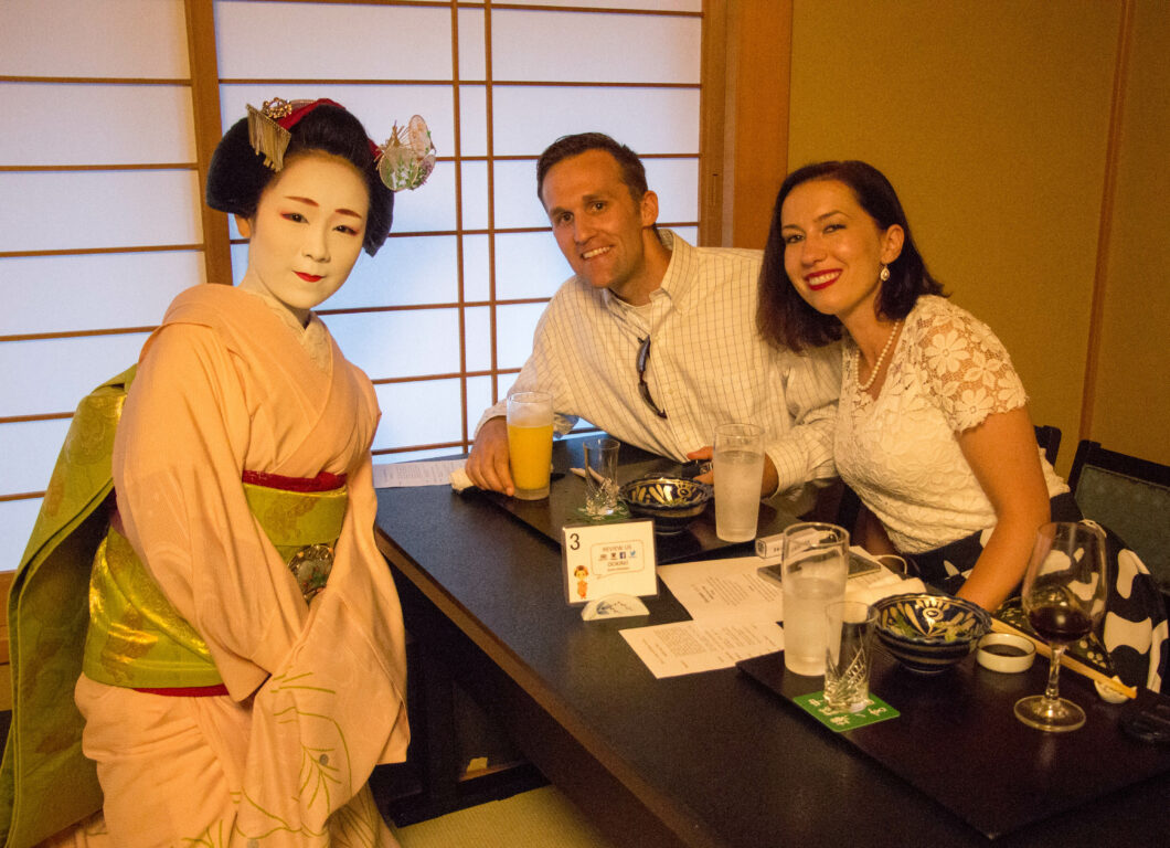 An American man and woman pose with a traditional Japanese Maiko, after enjoying tea together.