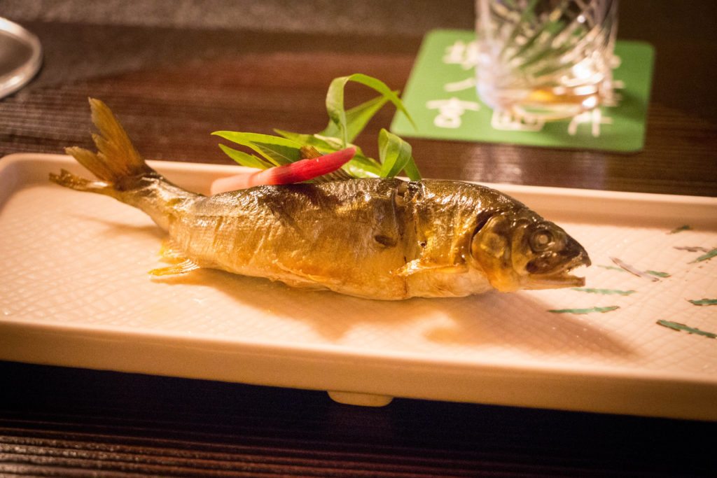 A whole cooked fish is served on a platter as part of a dining with a Geisha event.