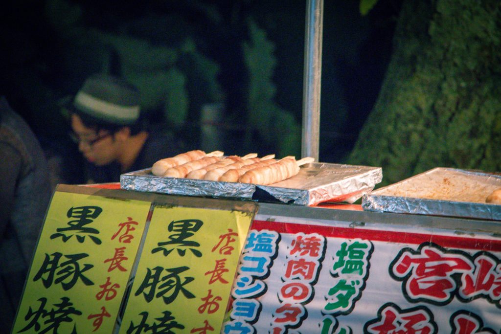 Japanese street food cooks on a foil-lined griddle.