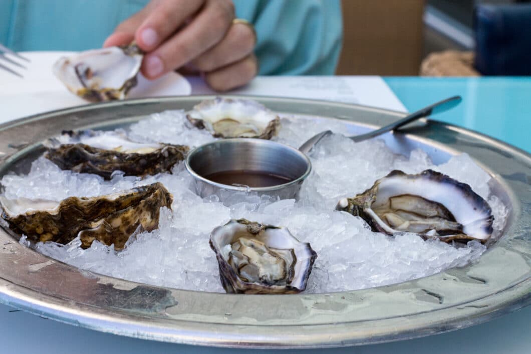 A plate of oysters served on ice with a bowl of sauce from Bondi Iceberg restaurant.