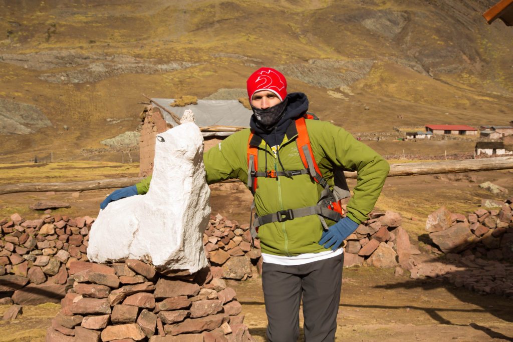 A man standing next to a statue of a Alpaca.