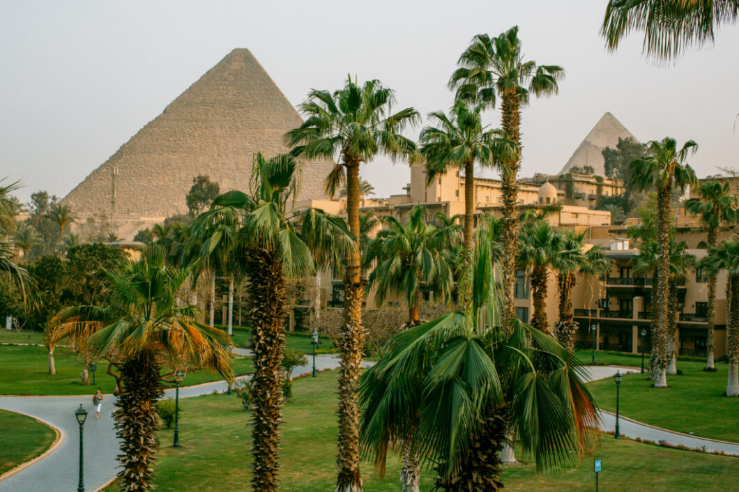 The view from our hotel room at Marriott Mena House overlooked the gardens - a lush courtyard with grass and tall trees, buildings, and the Pyramid of Giza in the background.