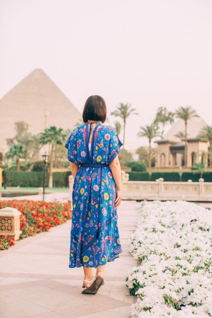 A woman wearing a blue dress in front of the pyramids at Mena House Cairo.