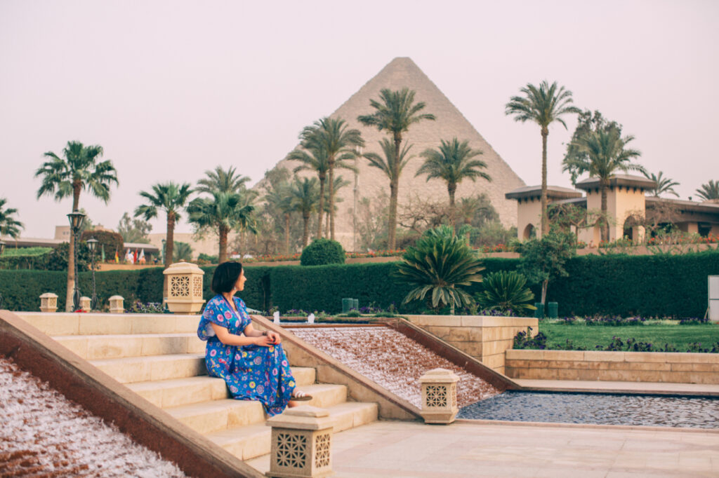 Lindsey of Have Clothes, Will Travel wearing a colorful maxi dress at Marriott Mena House in Cairo looking at the Pyramids of Giza.