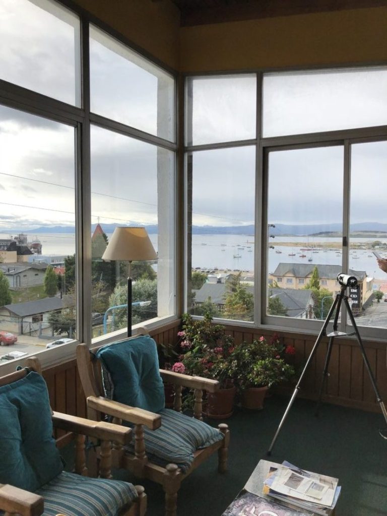 A living room with a large window overlooking the ocean at Hotel Mustapic in Ushuaia, Argentina.