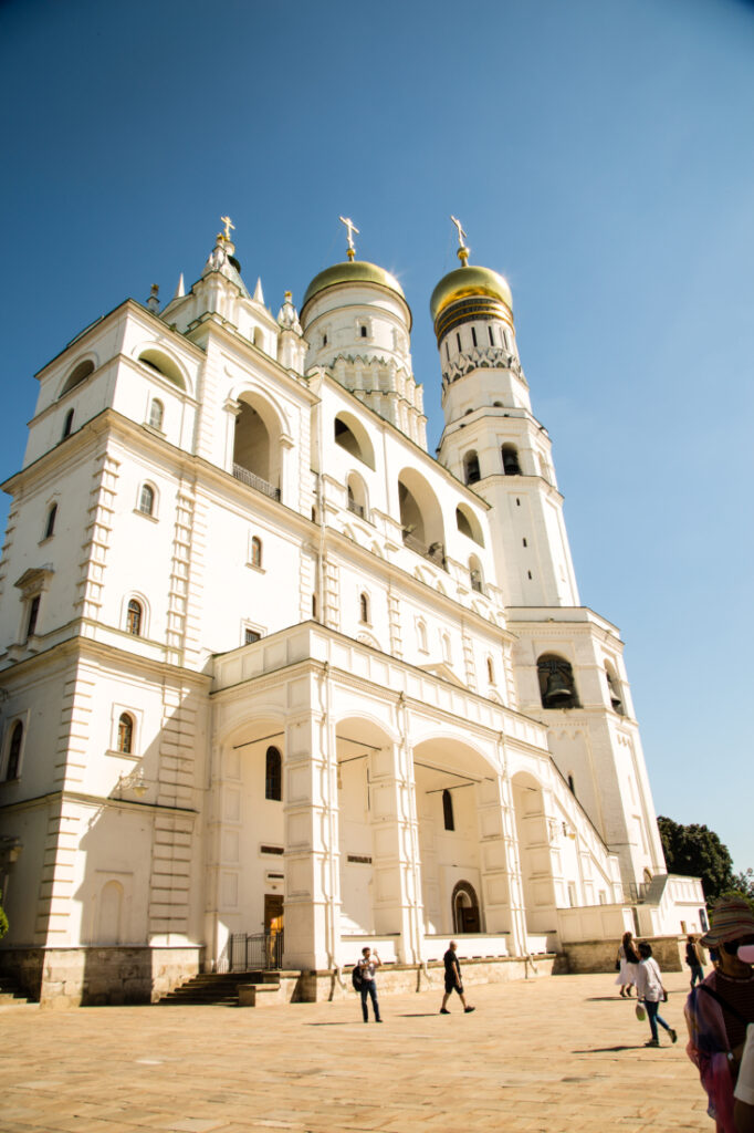 An exterior image of a large white building that is several stories tall, pictured against a blue sky. This building is one of the Kremlin Museums.