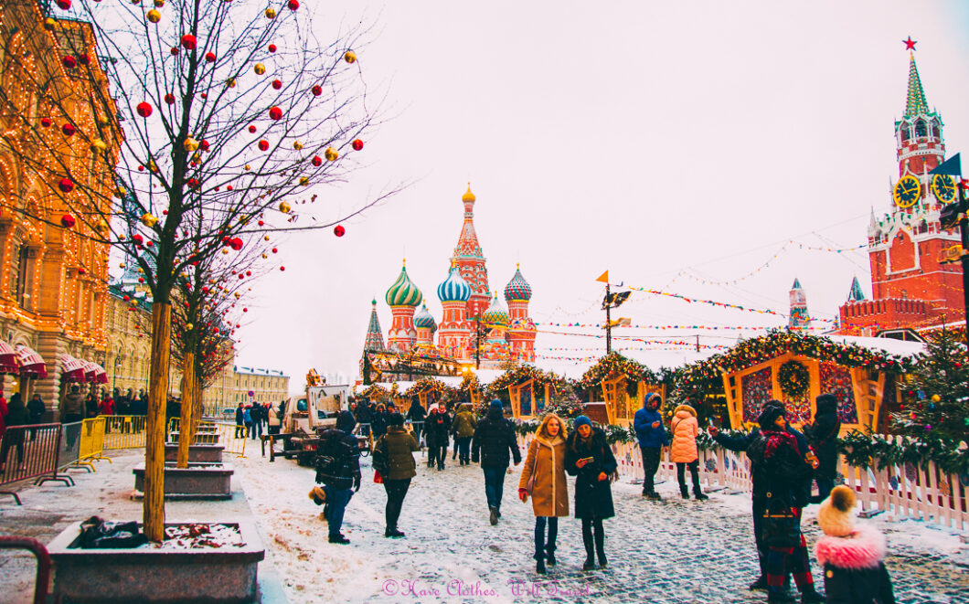 People walk through a snowy Christmas market in Moscow in The Red Square with St. Basil's Cathedral in the background.