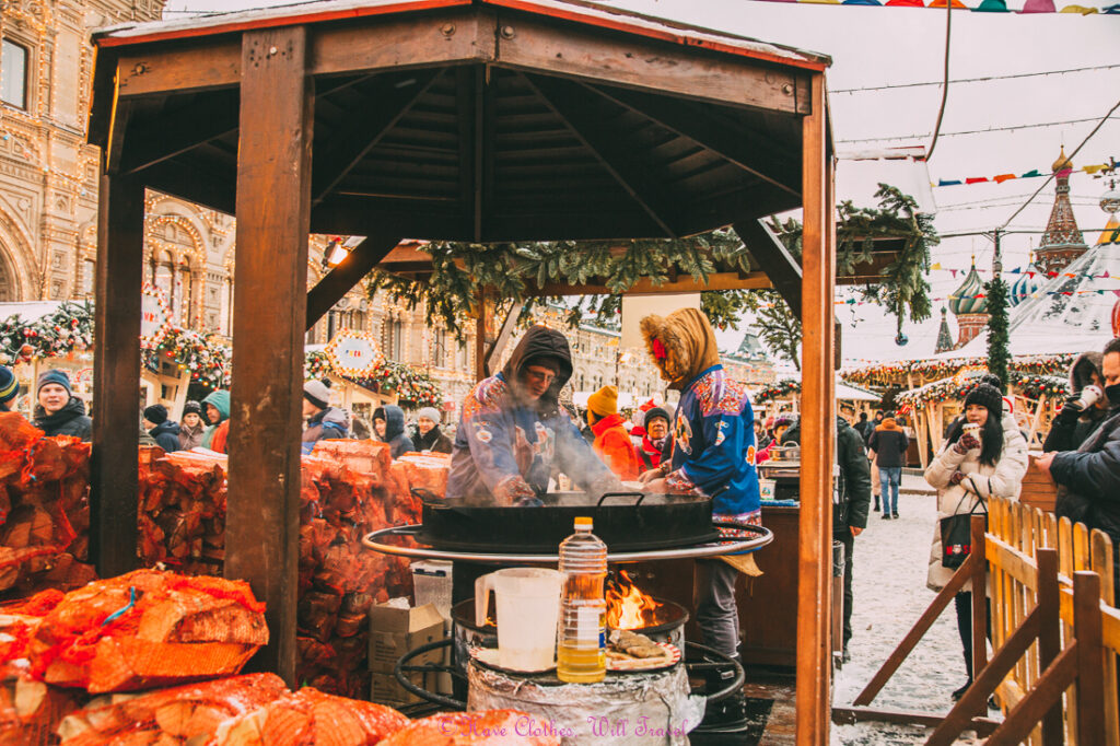 A food vendor at the Moscow Christmas Market prepares snacks for patrons on a cold winter day.