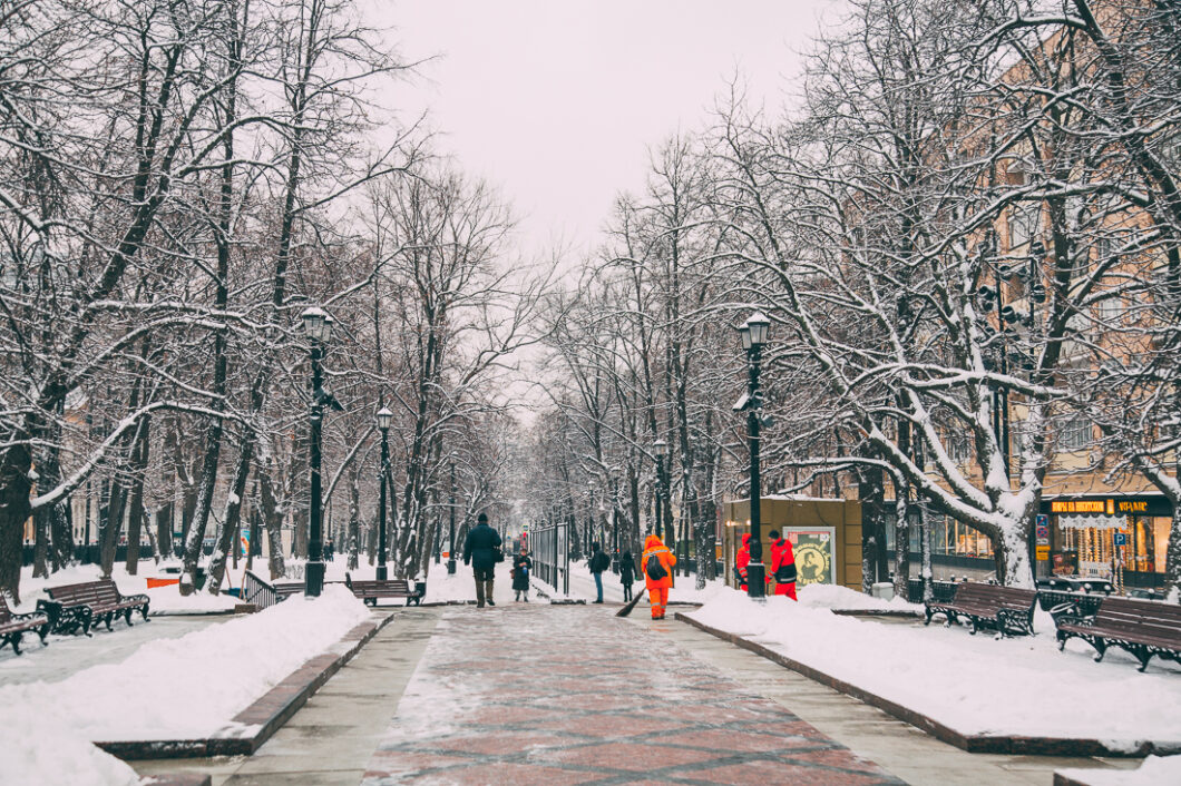 A walk through a snow-covered parkway in Moscow, Russia. Snow covers the naked tree branches as patrons walk through the canopy of trees.