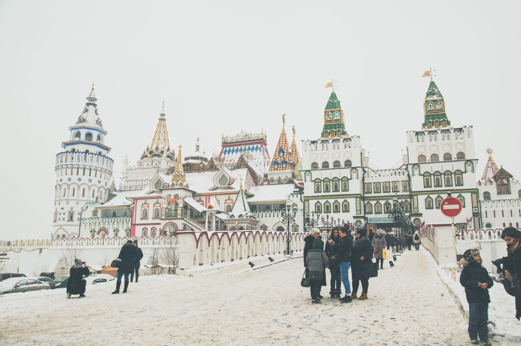 Snow-covered road leading to Izmailovsky Kremlin on a snowy winter day in Moscow, Russia. People walk up and down the street.