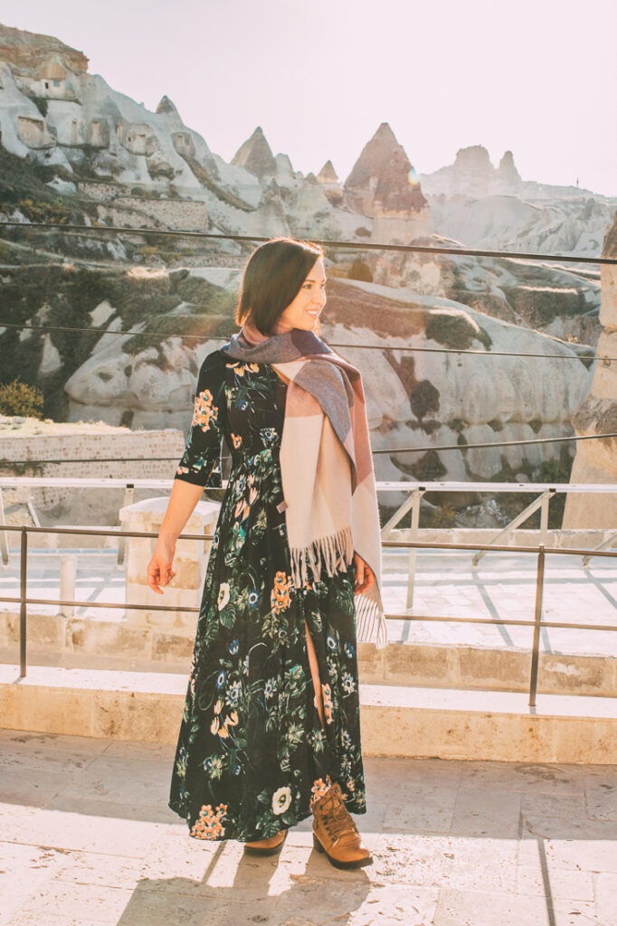 A woman wearing a floral dress and scarf in Cappadocia, turkey.