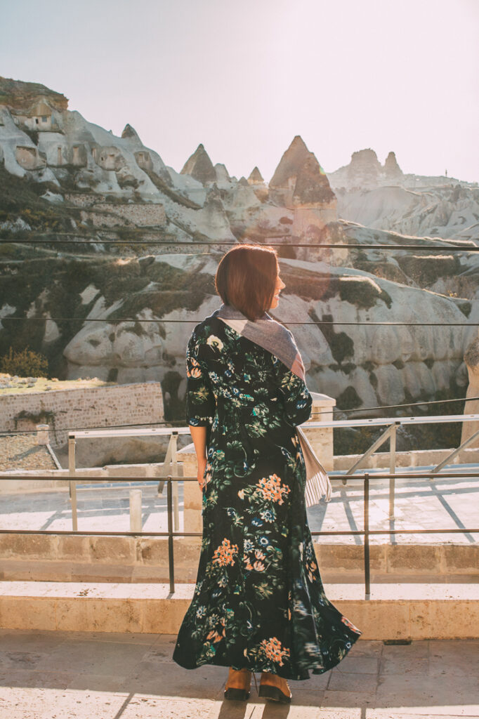 A woman in a floral dress standing in front of a mountain in Cappadocia, Turkey.