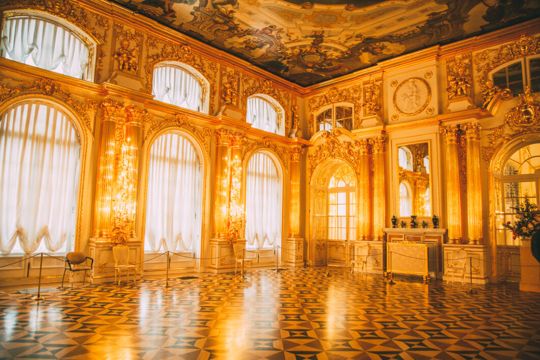 A grand hall inside Catherine Palace, covered with gilded gold and elegant parquet wood floors.