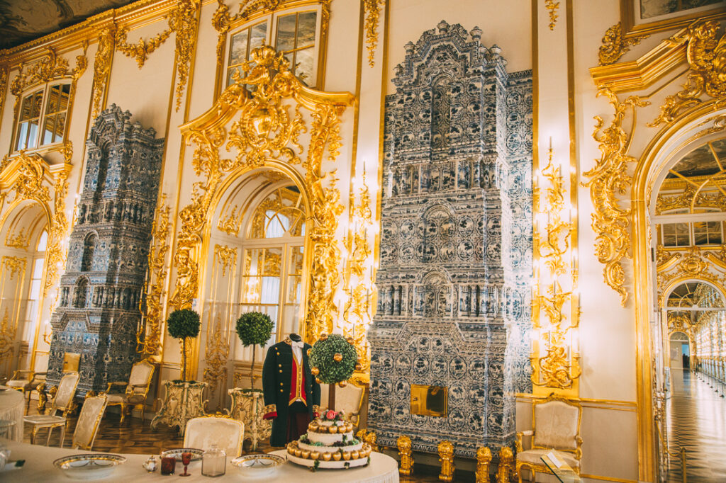 Another angle of a grand dining room inside Catherine Palace with ornate fireplaces that rise up against the gilded gold walls.