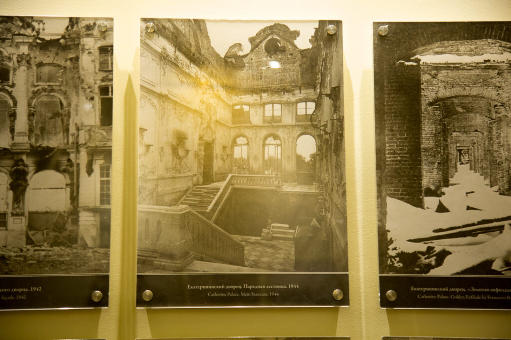 Three black and white photos of Catherine Palace before it's restoration, in display inside the palace.