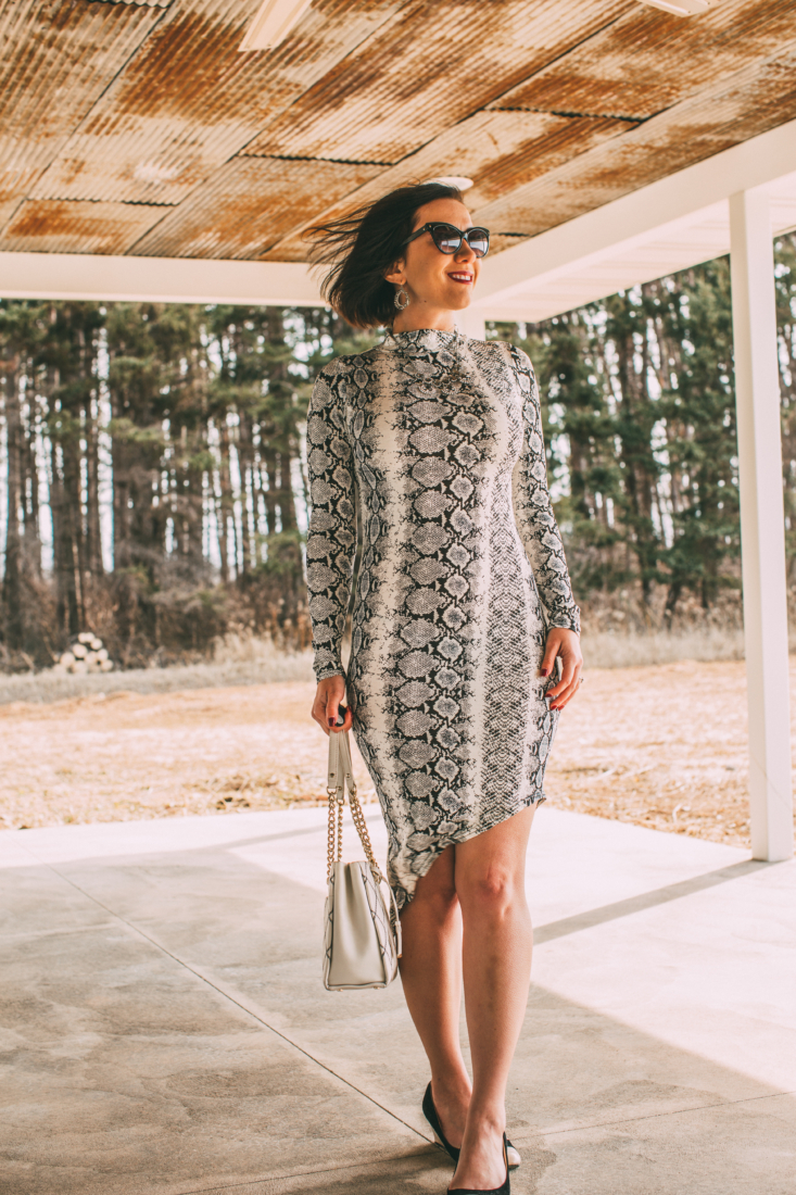 Front Pose of a women wearing Snakeskin Dress, holding a white bag 