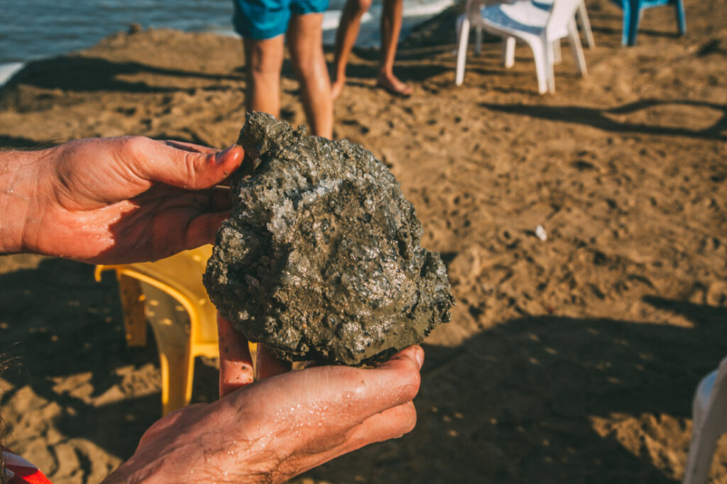A man holds a large chunk of natural sea salt pulled from the Dead Sea in his hands.