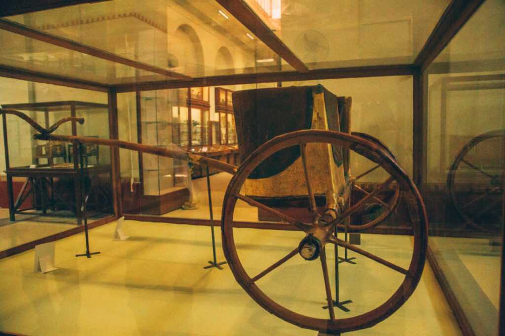 An ancient Egyptian carriage used to transport royalty is displayed inside a large glass case at the Egyptian Museum. 