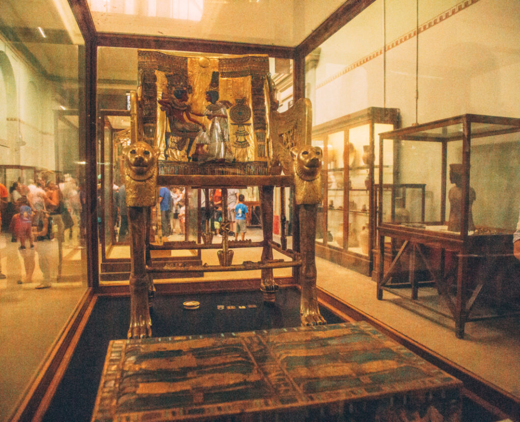 King Tut's Throne, an ornate chair decorated with ancient artwork and carvings, sits in a glass display case at the Egyptian Museum in Cairo.