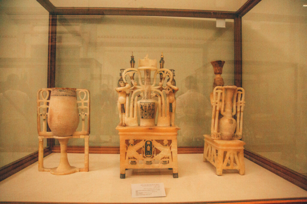 Intricate white marble jars and tubes used for storing King Tut's essential oils, on display inside a case at the Egyptian Museum.