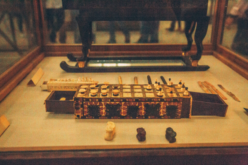An ancient Egyptian game similar to chess, complete with white and black pieces carved from stone, sitting inside a display case.