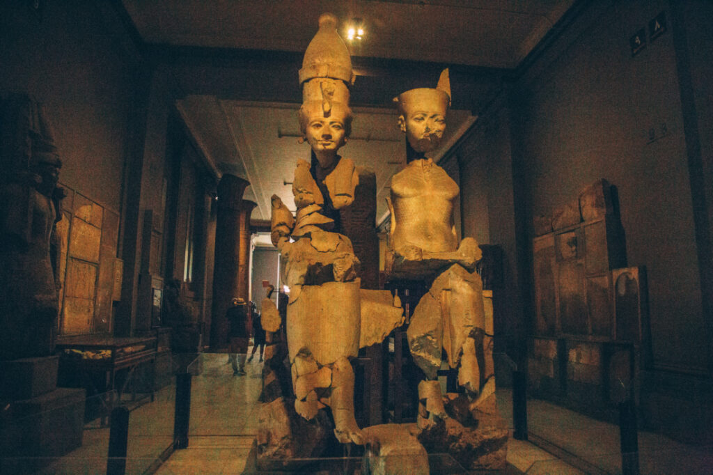 Two ancient statues carved from stone sit inside a glass display case at the Egyptian Museum.