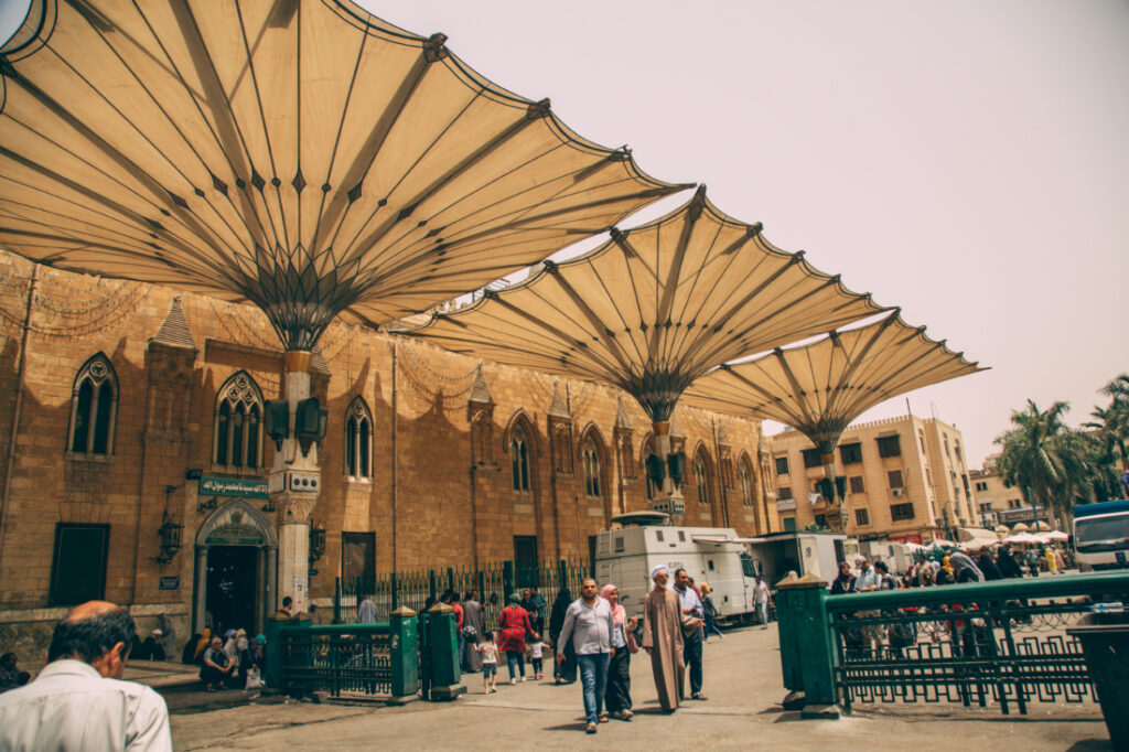 Giant cloth-covered canopies shade the streets of the Khan El Khalili Bazaar, where visitors and locals mill about the street.