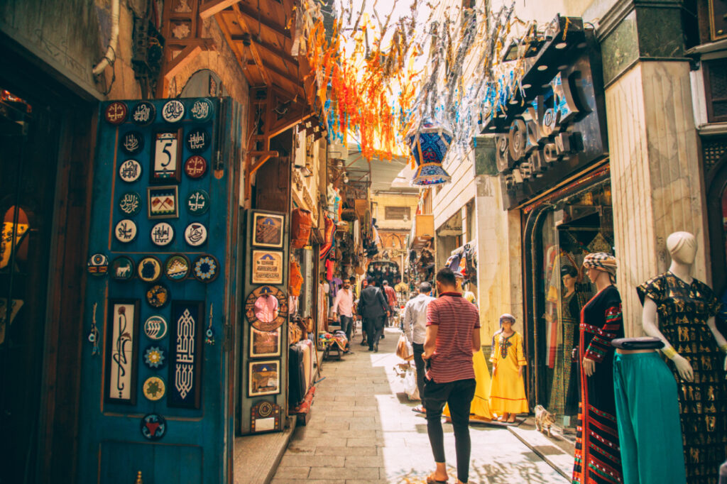 An alleyway at the Khan El Khalili Bazaar, filled with stalls, vendors, and shoppers.