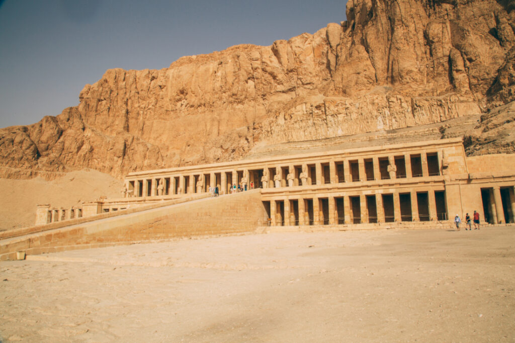 The entrance to the Temple of Hatshepsut is a long ramp that leads up to the temple, which is built into the side of a large cliff range.