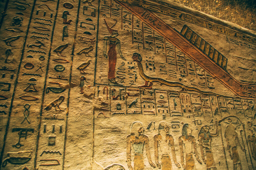 Ancient carvings of artwork and hieroglyphs line the stone wall inside of a tomb in the Valley of the Kings.