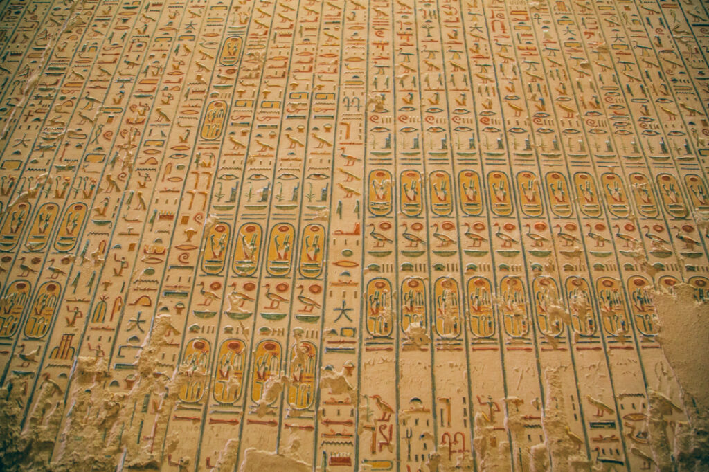 A stone wall filled with rows of colorful carved hieroglyphs inside a tomb at the Valley of the Kings.