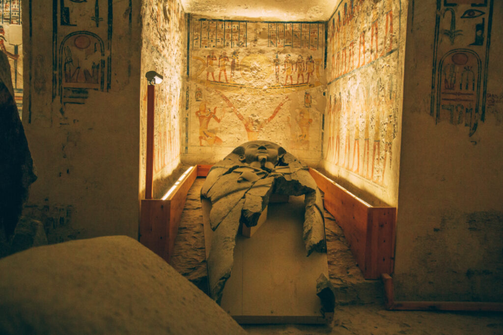 Remnants of a sarcophagus inside the tomb of Ramses V. The sarcophagus cover rests inside an art-covered alcove in the burial chamber.