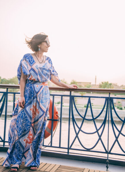 A woman wearing a modest, flowy blue dress on the top deck of the Amwaj Living Stone during a Nile River Cruise.