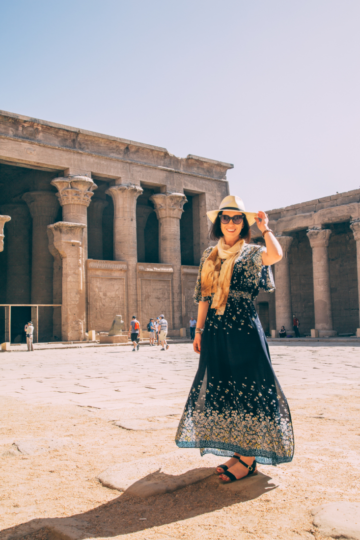 A woman wearing a Boho Split Tie-Waist Vintage Print Maxi Dress and hat in front of a temple. 