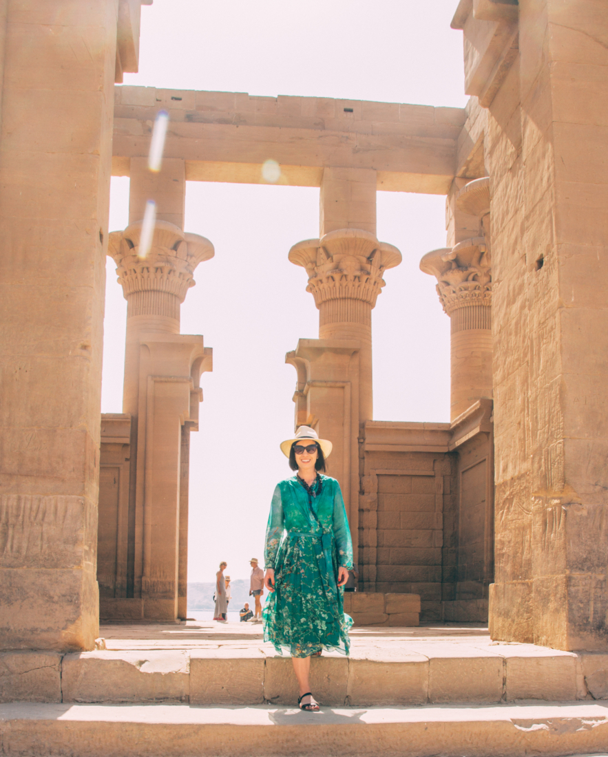 Lindsey of Have Clothes, Will Travel wearing a greenish blue silk dress in a temple in Aswan