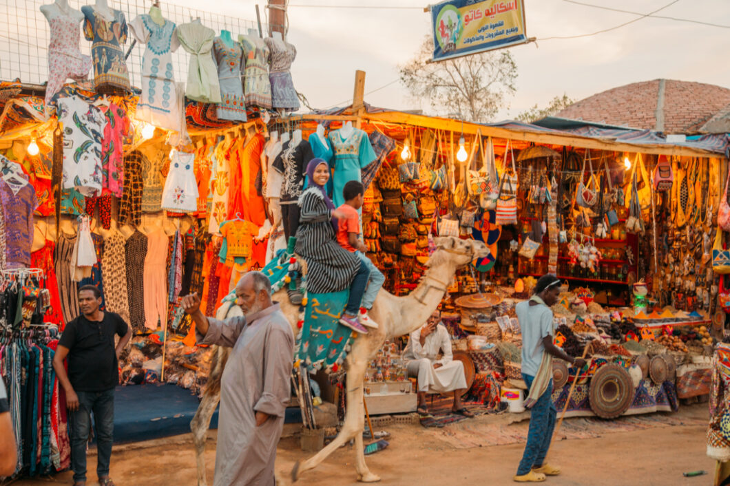 A woman riding a camel through the market in the Nubian Village of Aswan Egypt