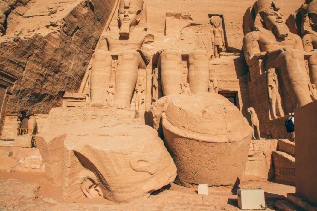 One of the crumbling Ramses II statues at Abu Simbel. The head and bust of the statue has crumbled into giant stone pieces that now sit at the feet of the other statues.