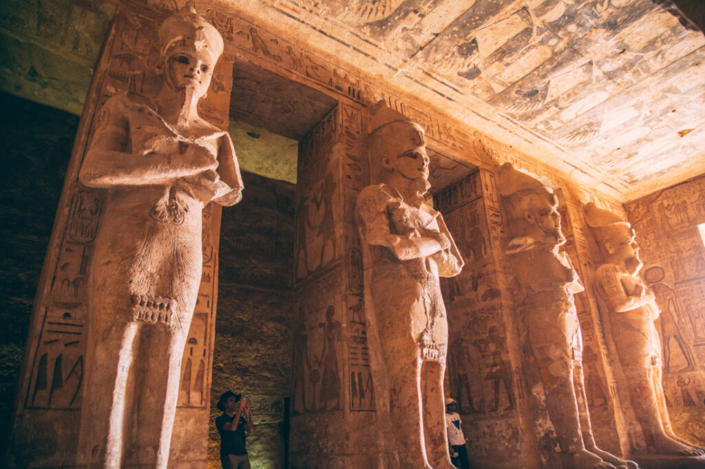 Four giant stone pillars rise to the ceiling, each with a different statue of Ramses II in Abu Simbel