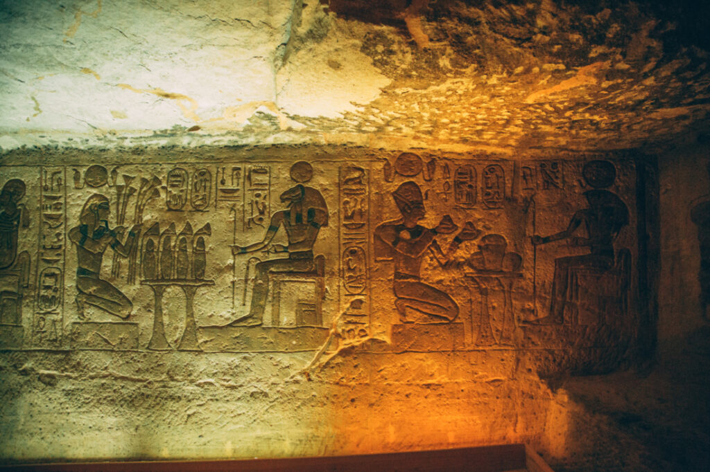 Dim green and orange lighting illuminated a series of carvings on a stone wall inside one of the two Abu Simbel temples.