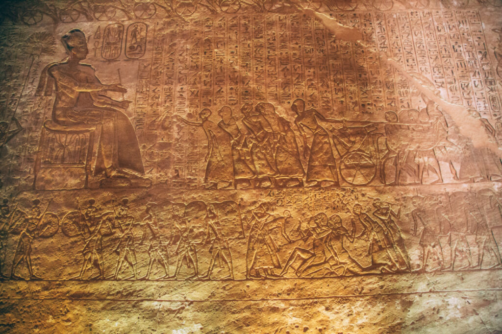 A close up image of various wall carvings on a stone wall inside the Abu Simbel temples.