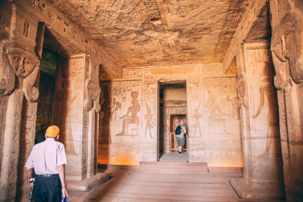 The grand interior entrance to one of the Abu Simbel temples, lined with stone pillars and walls covered in ancient artwork.