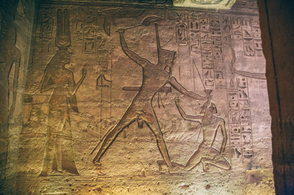 An image of one of the stone walls inside an Abu Simbel temple, covered in ancient carvings.