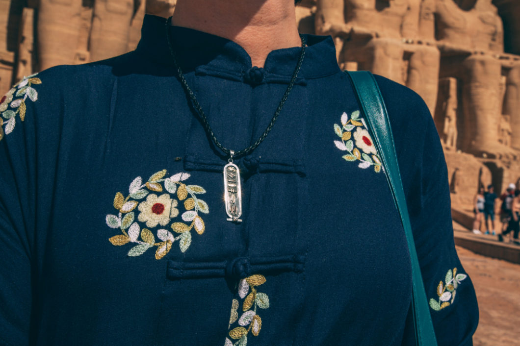 A woman wearing a hieroglyphics (cartouche) necklace.