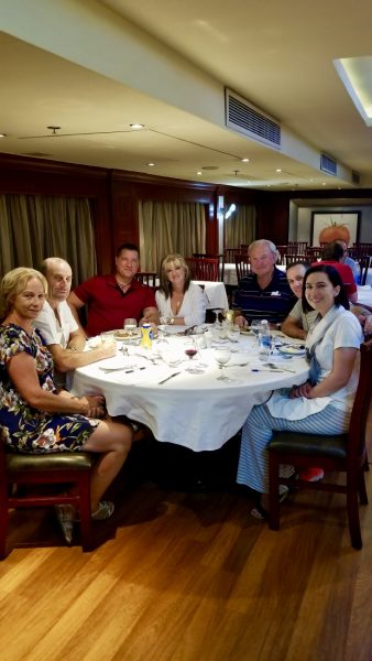 A group of tourists sitting on a dining table and smiling at the camera on the Amwaj Living Stone cruise on the Nile River.