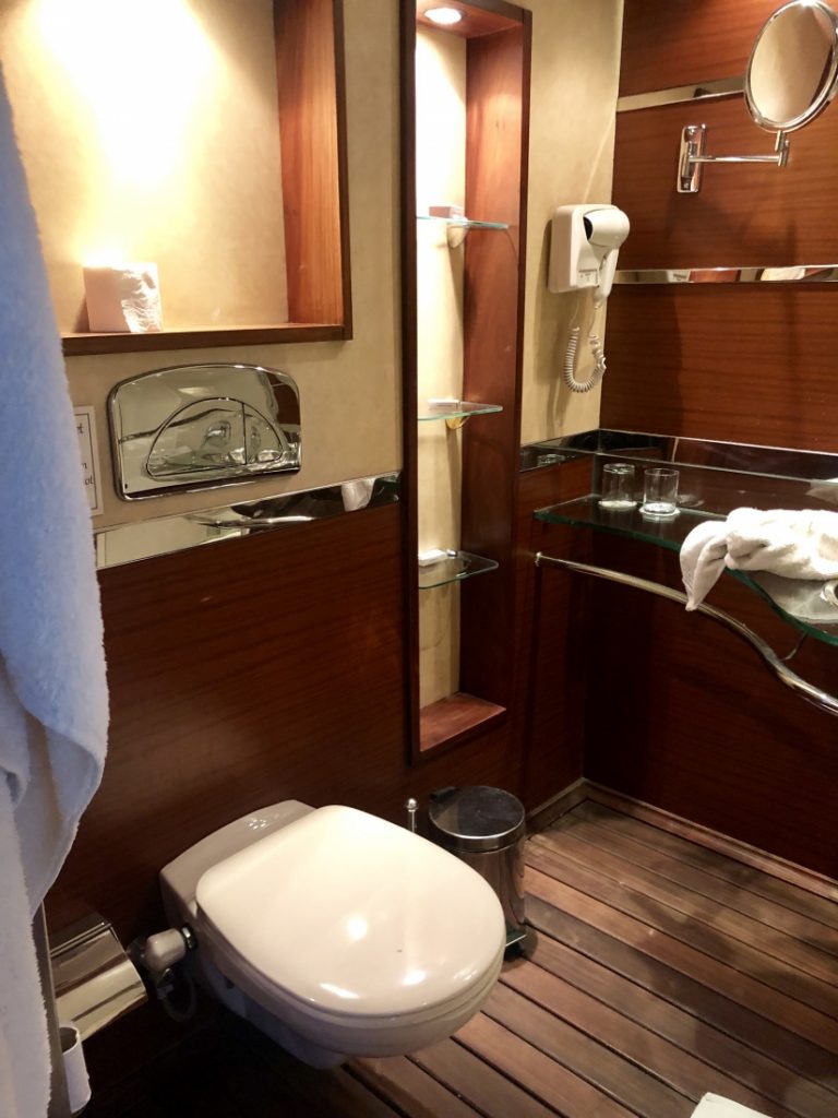 View of the bathroom on the Amwaj Living Stone Cruise with wood paneled floors and a hair dryer.
