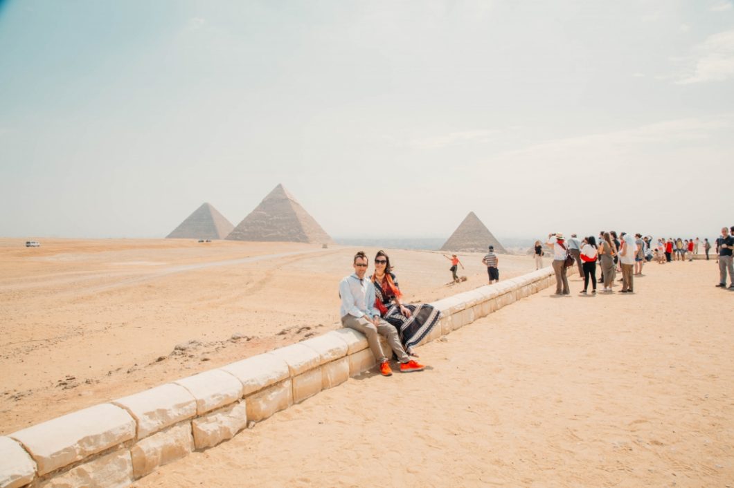 Crowds of people photographing the Egyptian pyramids on a sunny day.