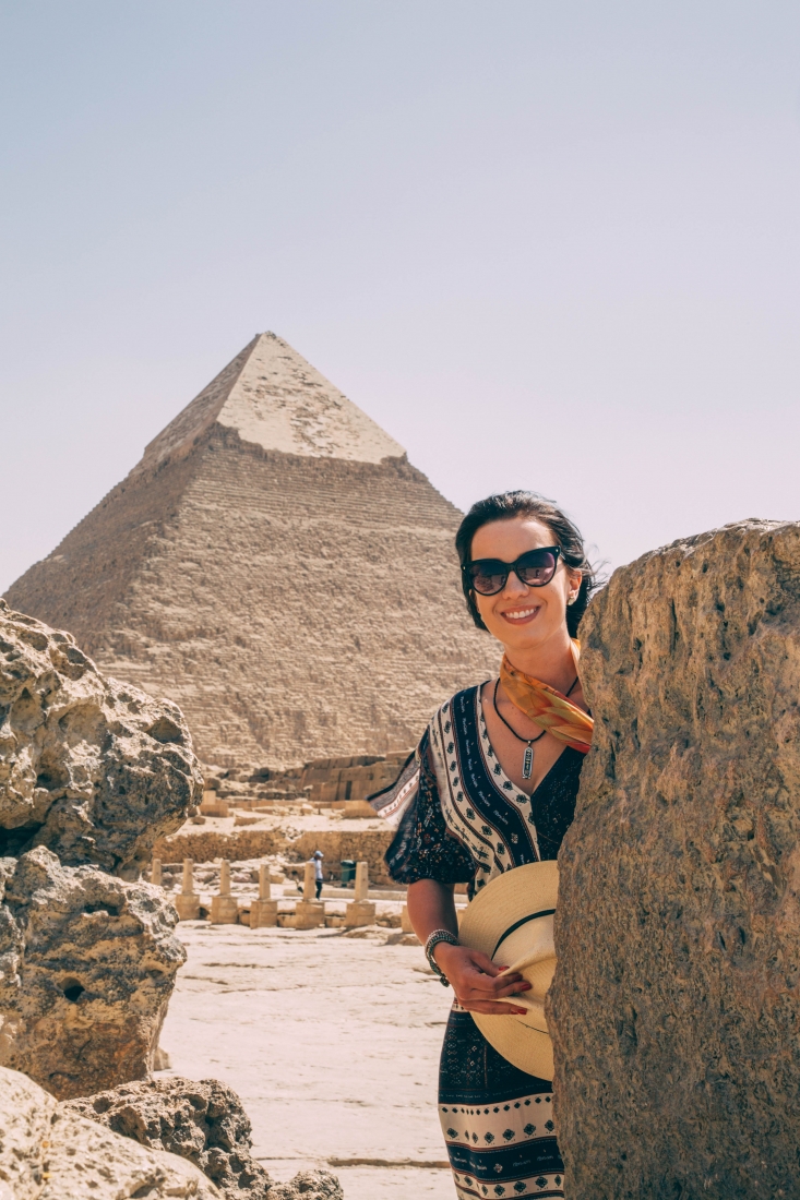 A woman is standing in front of the pyramids in giza, egypt.