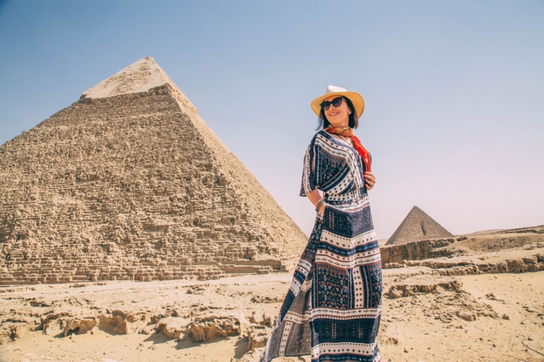 Lindsey of Have Clothes, WIll Travel wearing a fedora, sunglasses and Maxi dress at the Pyramids of Giza.