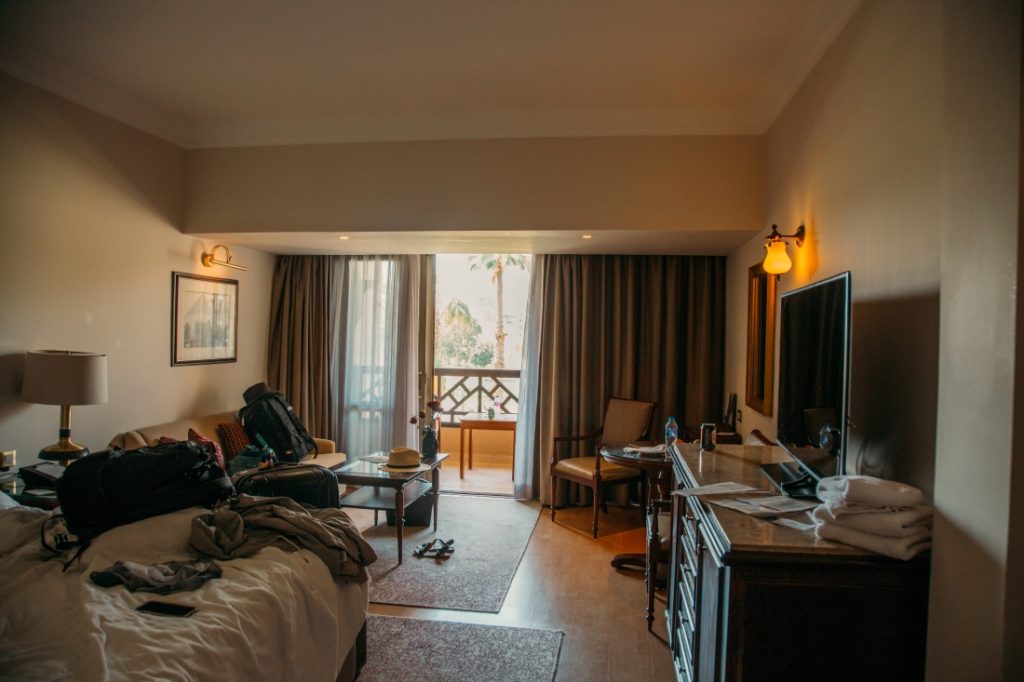 A photo of our king suite at Mena House Ciaro - a bed, sofa, dresser, and TV in the foreground, and balcony door covered by cirtains.