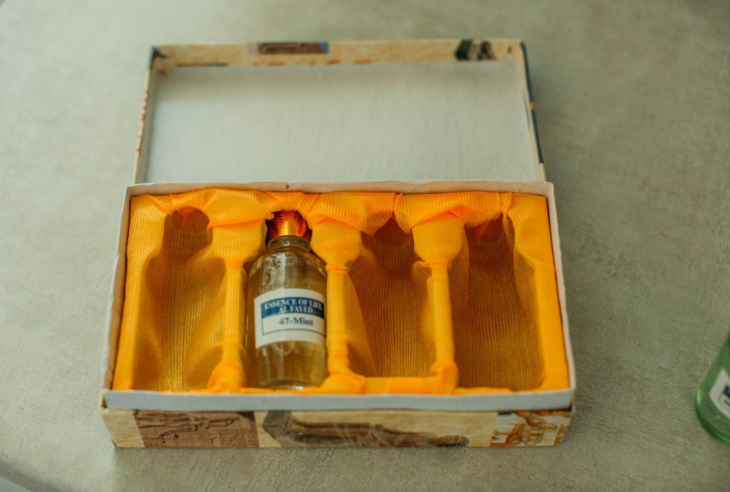 An essential oil box with one bottle and three empty slots on a white table. 